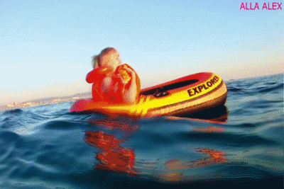 115239 - Alla swims on an inflatable boat on the sea, she's wearing an inflatable vest and inflatable wings on hand.