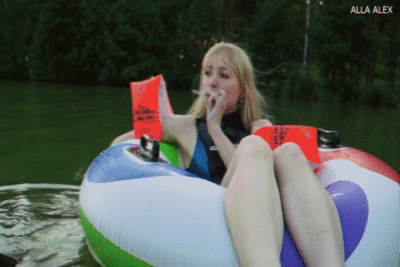 119746 - Alla is swimming in an inflatable ring on the lake and Smoking a cigarette.
